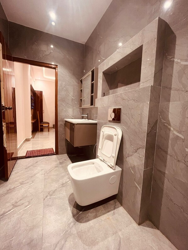 Un baño moderno con inodoro, lavamanos y espejo.