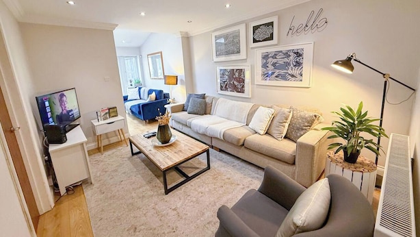 A modern living room with a sofa, armchair, coffee table, and a television.