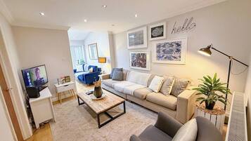 A modern living room with a sofa, armchair, coffee table, and a television.