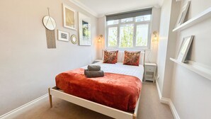 Una camera da letto ordinata con un letto, comodini e una finestra che lascia entrare luce naturale.