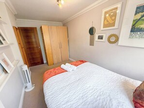 Un dormitorio con cama, armario, radiador y decoración en las paredes.