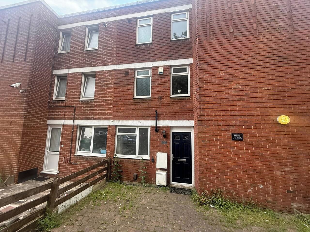 A multi-story brick building with a front door, windows, and a small outdoor area with steps.