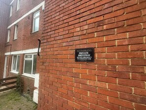 Un muro de ladrillo con un letrero que dice 'NO ESTACIONAR, PROPIEDAD PRIVADA'.