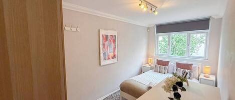 A bedroom with a bed, bedside tables, a window, and a door.