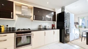 Una cucina moderna con piano cottura a gas, forno, frigorifero nero e mobili bianchi.