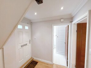A hallway with a white door, a wooden door, and a white wall.