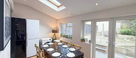A modern kitchen with a dining area, skylights, and a view of the garden.