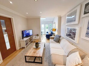 Een woonkamer met een televisie, een salontafel, een bank en een deur naar een andere kamer.