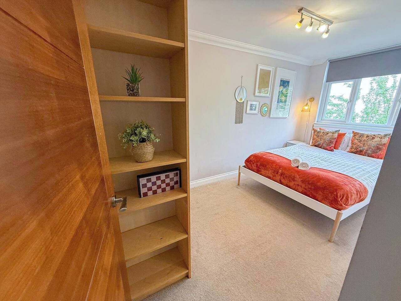 A bedroom with a bed, a wooden wardrobe, and a window.