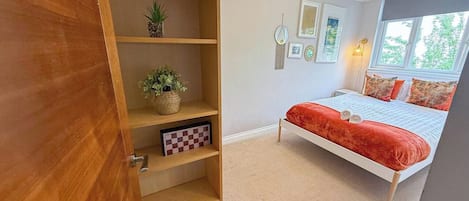 A bedroom with a bed, a wooden wardrobe, and a window.