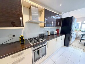 Cozinha moderna com fogão a gás, forno e geladeira preta.