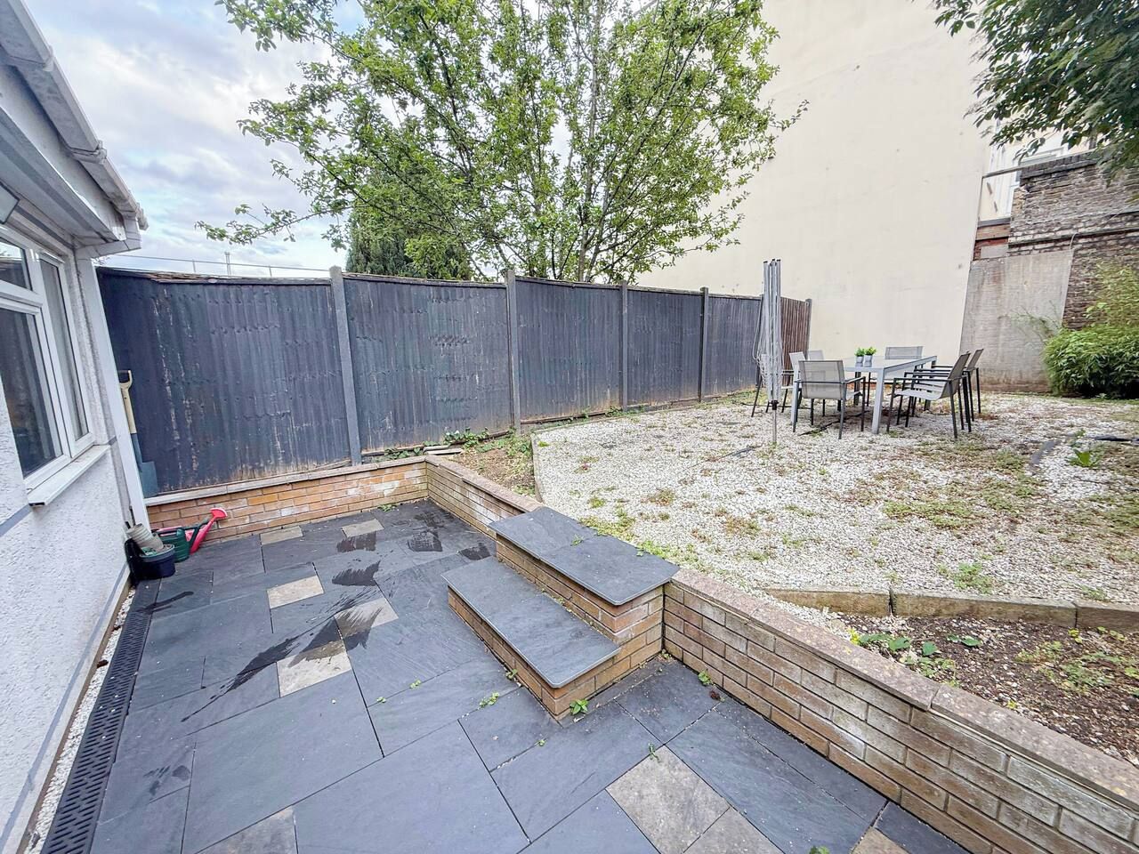 A backyard with a patio area, a seating arrangement, and a wooden fence.