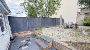 A backyard with a patio area, a seating arrangement, and a wooden fence.