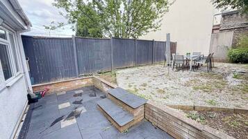 A backyard with a patio area, a seating arrangement, and a wooden fence.