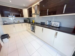 Een moderne keuken met witte kastjes, een zwart aanrecht en roestvrijstalen apparatuur.
