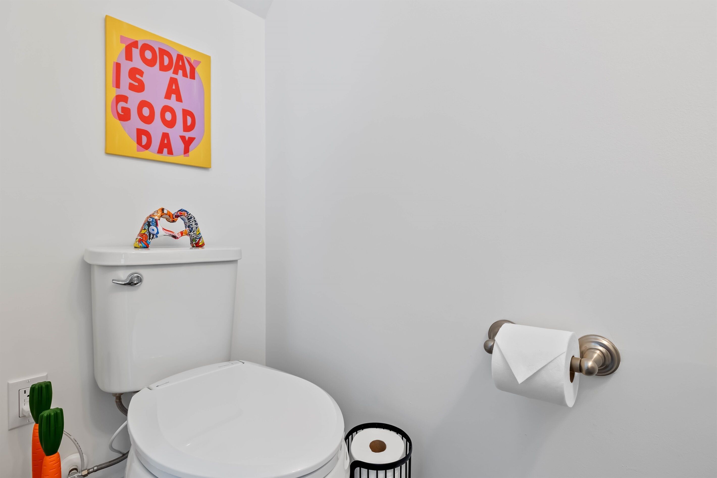 Une salle de bain équipée de toilettes, d’un porte-rouleau de papier toilette et d’une affiche motivante au mur.