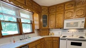 A kitchen with wooden cabinets, a microwave, an oven, and a dishwasher. - Charming 3 Bedroom House away from it all but Close to everything (Odessa)