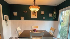 A dining area with a dark green wall, white wainscoting, a chandelier, and a checkered floor. - Charming 3 Bedroom House away from it all but Close to everything (Odessa)