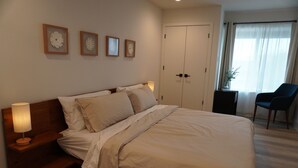 Una habitación de hotel con una cama grande, lámparas de noche, una silla y un armario.