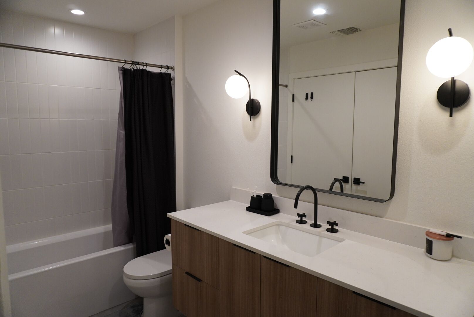 A modern bathroom with a white sink, black faucet, and a large mirror.