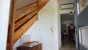 A wooden staircase leading to a bedroom, a wooden chest of drawers, and a hallway with a door and a wall-mounted air conditioner. - La Villa de Font-Romeu (Font-Romeu-Odeillo-Via)