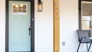 A house with a light blue door, a wooden post with the number 822, and a chair outside. - Chic 2BR/2BA Near Dining & Shops (Winston-Salem)