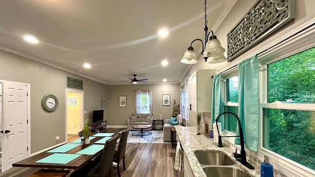 A spacious kitchen with a granite countertop, a sink, and a dining area with a long table and chairs. - Chic 2BR/2BA Near Dining & Shops (Winston-Salem)
