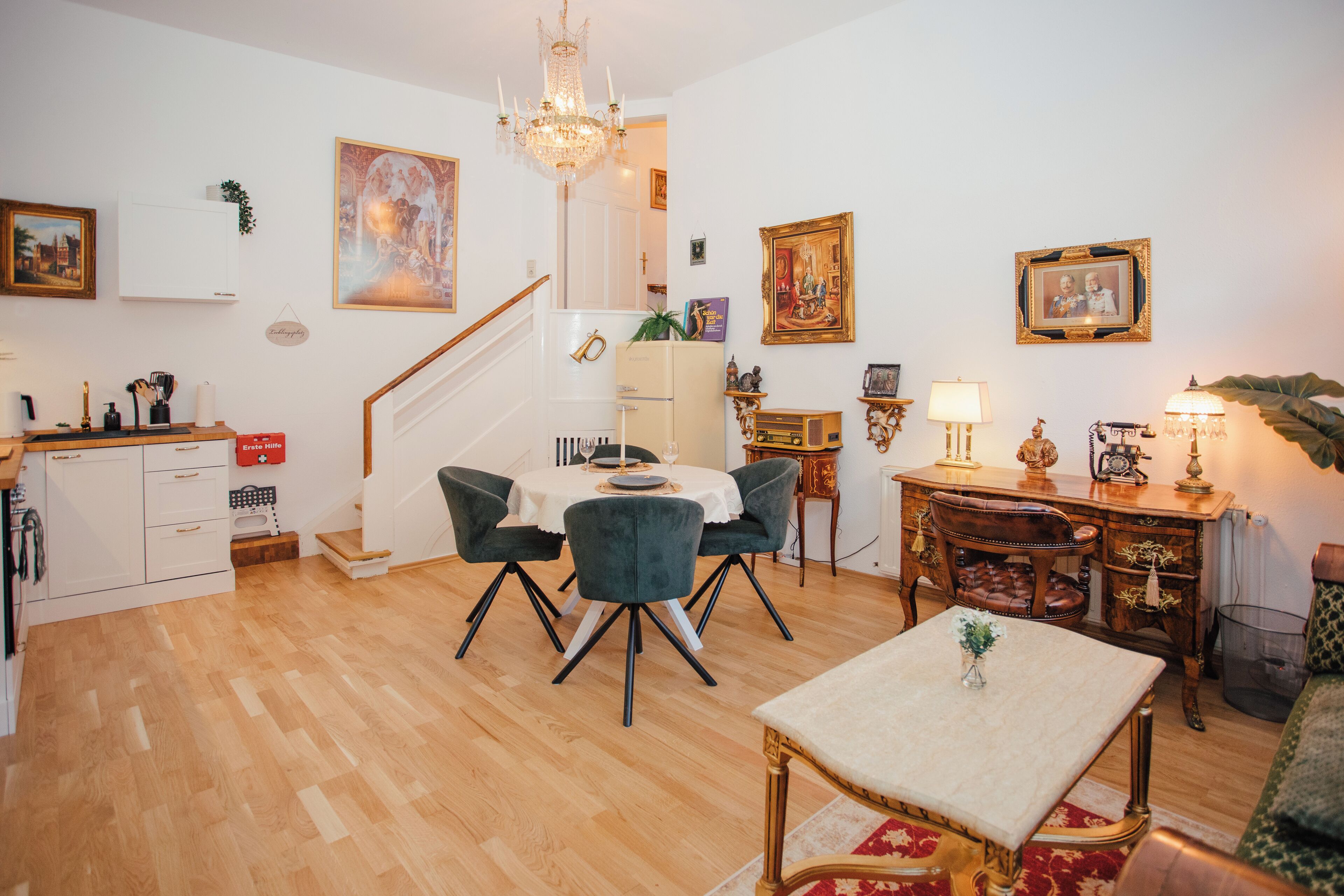 A dining area with a table and chairs, a chandelier, and a staircase leading to another level.