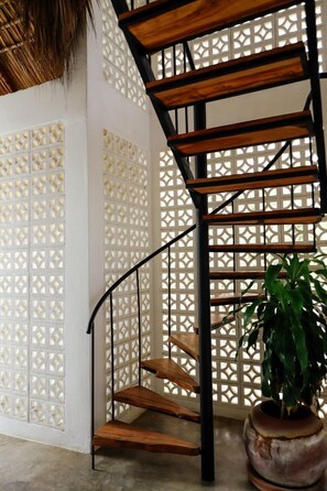 A spiral staircase with wooden steps and black metal railings, surrounded by white lattice panels. - Casa Areka (Brisas de Zicatela)
