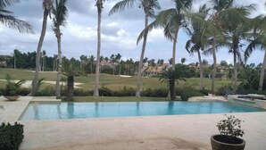 A swimming pool with a view of a golf course and palm trees.