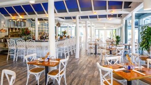 Un restaurant spacieux avec de hauts plafonds, des chaises blanches et des tables en bois.