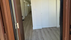 A hallway with wooden flooring, white doors, and a framed sign on the wall.