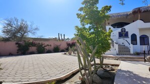 A courtyard with a cactus, a building with a white facade and blue accents, and a clear blue sky. - 10 Minute Walk to Pickleball and the Sea of Cortez (Los Barriles)