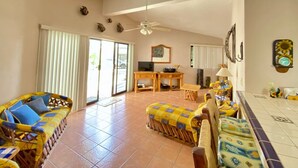 A spacious living area with a ceiling fan, a dining table, and a sofa set. - Cozy Home One Off the Beach (Spa Buena Vista)