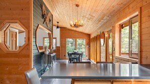 Un interior de madera con una isla central, ventanas amplias y un candelabro.