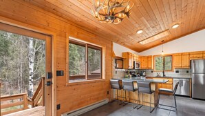 Una cocina moderna con armarios de madera, un refrigerador de acero inoxidable y una zona de bar con taburetes.