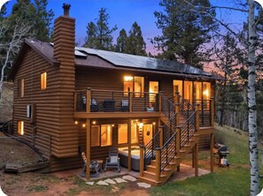 Une cabane en rondins dotée d’un balcon, d’un espace salon extérieur et d’un jacuzzi.
