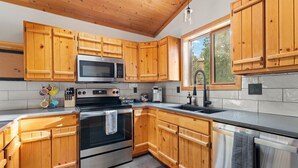 A kitchen with wooden cabinets, stainless steel appliances, a window, and a tiled backsplash.