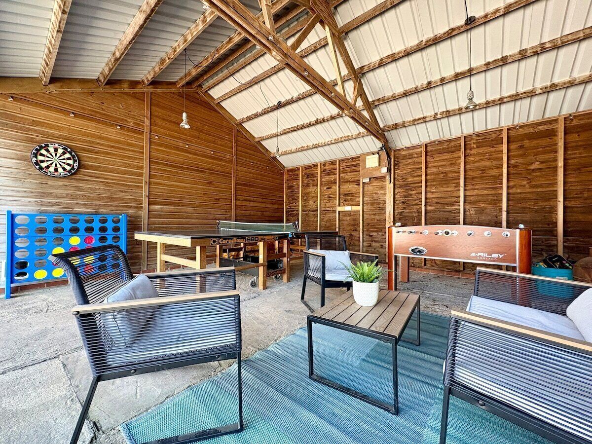 An indoor recreational area with a ping pong table, seating, and a foosball table.
