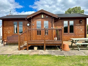 A wooden cabin with a deck, a bench, and a picnic table. - Beautiful Danford House & Lodge with Hot Tub (Hartpury)