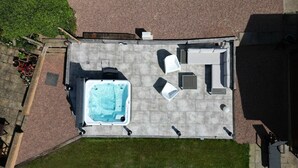 Luchtbeeld van een terras met een jacuzzi, zitplaatsen en een kleine tuin.