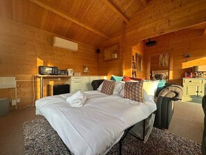 Ein Schlafzimmer einer Holzhütte mit Bett, Schreibtisch, Fernseher und Kleiderschrank.