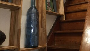 Una estantería de madera con varios objetos, como libros, una botella azul y carteles enmarcados.