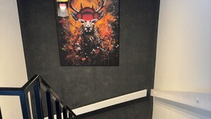 A staircase with a modern design, a dark wall, and a framed artwork of a deer.