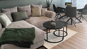 A modern living room with a sectional sofa, a coffee table, and a dining area with chairs.