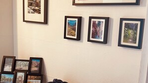A wall with multiple framed photographs, a wicker basket with towels, and a vase with dried flowers. - Charming 3-bedroom house with AC, WiFi in phenomenal Phoenix (Phoenix)