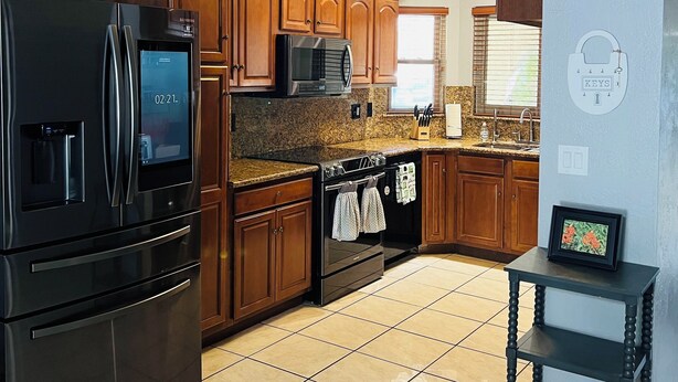 A modern kitchen with dark wood cabinets, stainless steel appliances, and a granite countertop. - Charming 3-bedroom house with AC, WiFi in phenomenal Phoenix (Phoenix)