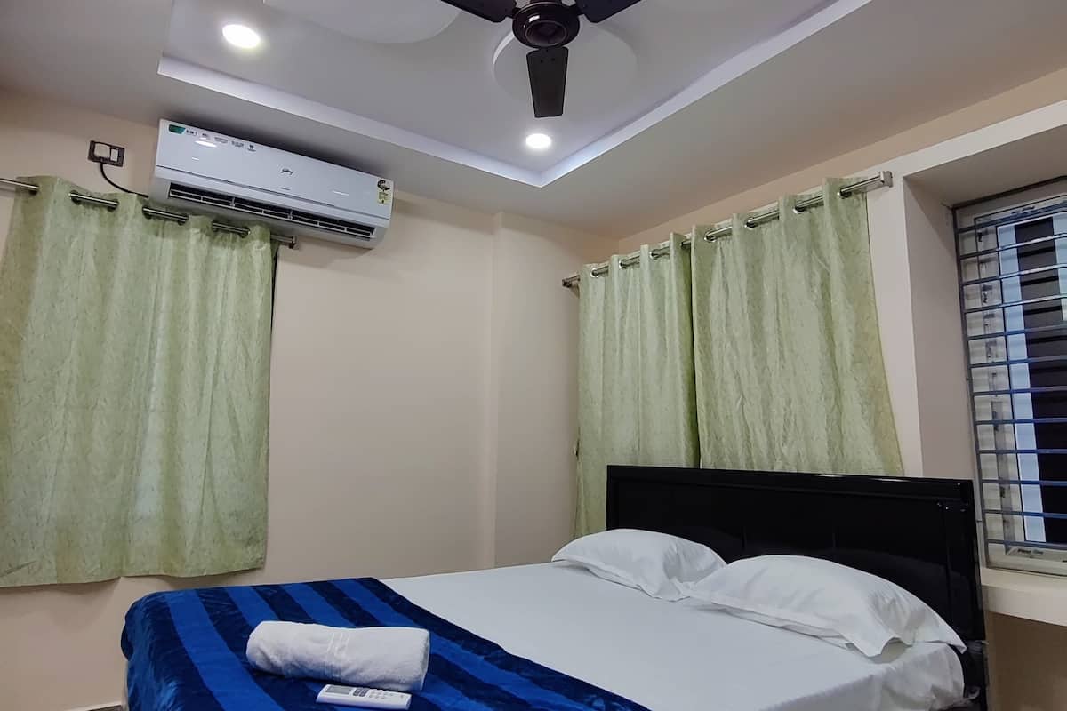 A bedroom with a bed, an air conditioning unit, a ceiling fan, and curtains.