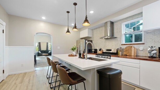 A modern kitchen with a central island, bar stools, pendant lighting, and a view into the dining area. - Beautiful 3BR/2.5 BTH PERFECT location in Short North/Campus w/HUGE 4 car garage (Columbus)