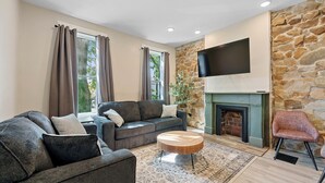A living room with a fireplace, stone wall, and a flat-screen TV. - Beautiful 3BR/2.5 BTH PERFECT location in Short North/Campus w/HUGE 4 car garage (Columbus)